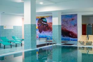 巴甫洛达尔Hotel Сomplex Irtysh的一个带椅子的游泳池,墙上挂着一幅画