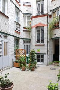 巴黎圣赫尔蒙巴克公寓的一座种植盆栽植物的建筑前的庭院