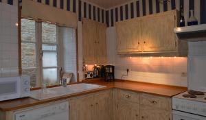 斯帕Le Petit Maur的厨房配有木制橱柜和白色水槽。