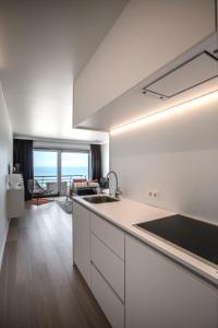 奥斯坦德海景一室公寓的一间厨房,配有白色的橱柜,享有海景