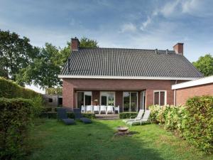 伦德Luxurious holiday home with wellness, in the middle of the North Brabant nature reserve near Leende的砖屋,配有白色椅子和庭院