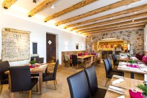 Nieder-Olm达斯克拉斯旅馆的一间设有木桌和椅子的餐厅以及石墙