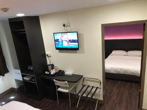 新加坡L Hotel at 51 Desker的客房设有床、书桌和电视。