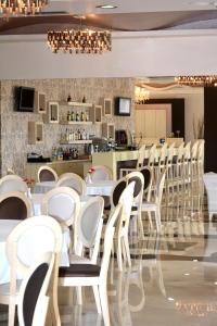 马尔马里埃维亚套房酒店的一间设有白色椅子的餐厅和一间酒吧