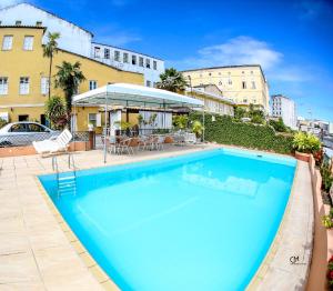 萨尔瓦多波萨达达曼格拉酒店的一座大型蓝色游泳池,位于大楼旁边