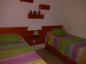法马拉Famara Paraíso的卧室内的两张床,配有绿色和多彩的床单