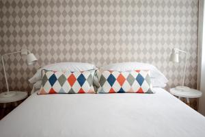 马德里60 Balconies Art的一间卧室配有一张带两个枕头和一面墙的床。