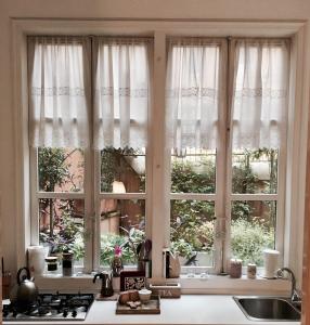 罗马维亚德洛卡35号公寓的厨房窗户配有白色窗帘和水槽