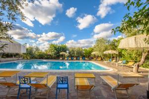 弗切瓦拉诺花园Il酒店的度假村的游泳池配有桌椅和遮阳伞