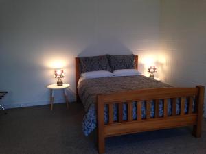 奥玛鲁阿伦经济公寓的一间卧室配有一张木床和两盏灯。