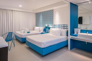 长滩岛柯伦特阿斯托里亚酒店的一间卧室设有两张床、一个水槽和一个浴缸