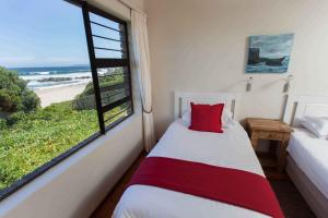 普利登堡湾亚赤洛克度假酒店的一间卧室设有一张床和一个享有海滩美景的窗户。