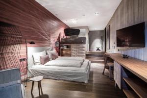 滨湖采尔Senses Violett Suites - Adults Only的一间卧室配有一张床、一张书桌和一台电视。