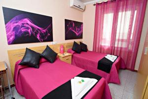 埃尔达Hostal Carrizo的一间设有两张粉红色床单的床的房间