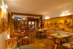 策拉-梅利斯Pension Zum Schotten的餐厅设有桌椅,墙上挂有绘画作品
