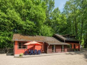 韦姆Modern Holiday Home in Waimes near Lake的一座红色的小建筑,配有椅子和雨伞