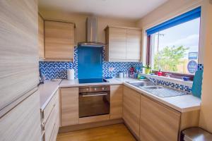 克雷尔Beach House Walk - Crail - Home from Home的厨房配有木制橱柜、水槽和窗户。