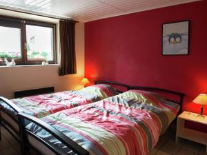 韦姆Child friendly Holiday Home in Waimes with Sauna的一间卧室设有两张床和红色的墙壁