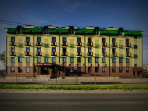 普斯科夫卡梅罗公寓式酒店的一座黄色的大建筑,有绿色的屋顶