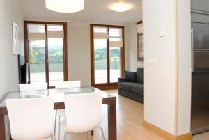 扎鲁亚斯塔莱门迪旅游公寓酒店的客厅配有玻璃桌和白色椅子