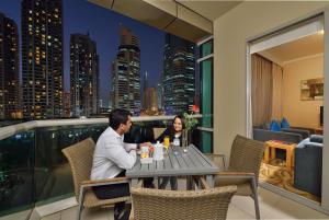 迪拜Oaks Liwa Heights Hotel Suites的坐在阳台上桌子上的男人和女人