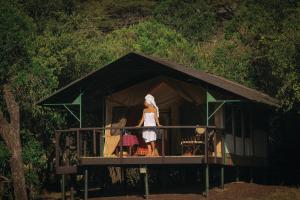 OlolaimutiekSekenani Camp Maasai Mara的站在房子阳台上的妇女