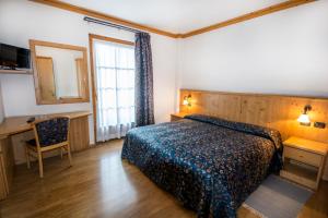 博尔米奥花园酒店的一间卧室配有一张床、一张书桌和一个窗户。