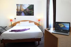 巴黎德拉图尔酒店 的一间卧室配有一张床和一张桌子上的笔记本电脑