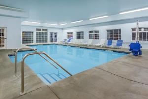 斯波坎谷SilverStone Inn & Suites Spokane Valley的大楼内带蓝色椅子的大型游泳池