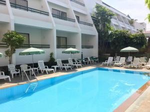华欣华欣斯里酒店的一座设有游泳池、椅子和遮阳伞的酒店