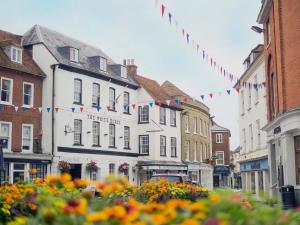 拉姆西The White Horse Hotel, Romsey, Hampshire的一条有建筑、旗帜和鲜花的城市街道