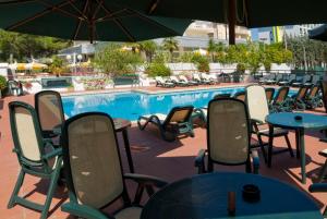 比比翁Hotel Concordia 3S的一个带桌椅和遮阳伞的游泳池