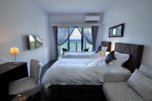 北谷町Beach Front Tower Mihama by DSH的一间卧室配有一张床、两把椅子和一个窗户