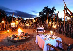 斯库库扎Jock Safari Lodge的晚间海滩上带灯的餐桌