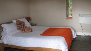 Boldre特夫卡特斯阿姆斯宾馆的一间卧室配有一张白色的床和橙色毯子