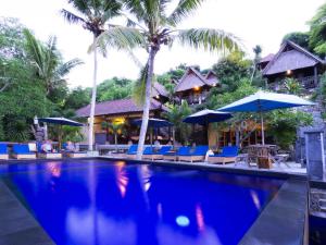 蓝梦岛桑兰邦吉海滩小屋酒店的度假村的游泳池,配有椅子和遮阳伞