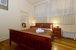 霍巴特爱丁堡画廊旅馆的一间卧室配有一张带木制床架的大床