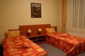 维尔纽斯天堂汽车旅馆的一间卧室设有两张床和一张带台灯的桌子。