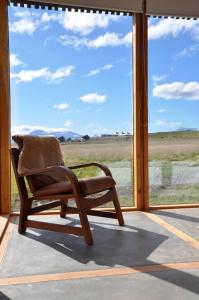 纳塔列斯港Hotel Simple Patagonia的摆在大窗户前的摇椅