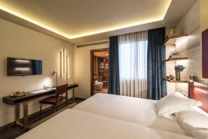 巴塞罗那文希梅酒店的一间酒店客房,配有一张白色的床和一张书桌