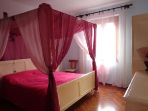 奥斯塔Appartamento Fantasia CIR Aosta 0241的一间卧室配有一张粉红色的床和天蓬