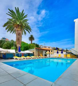 圣港普拉亚多拉达酒店的一个带棕榈树和椅子的大型游泳池