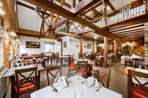 埃尔布隆格麦恩水上Spa酒店的餐厅设有白色的桌椅和木制天花板。