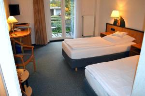 伦格里希Hotel Zur Mühle的酒店客房设有两张床、一张书桌和一个窗户。