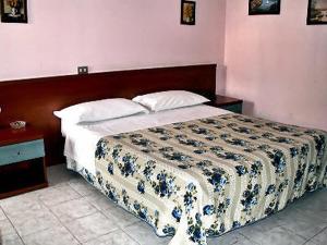 米兰拉力酒店的一间卧室配有一张大床和木制床头板