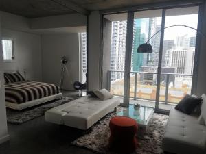 迈阿密Downtown Miami Deluxe Apartment的一间卧室配有一张床、一张沙发和一个窗口