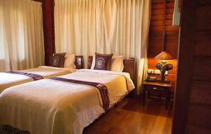 Amphoe Sawang Daen Din查塔帕雅度假村的一间卧室配有两张床和一张带台灯的桌子