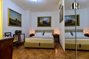 罗马Elite Rome Apartments的白色客房的两张床,墙上挂有绘画作品