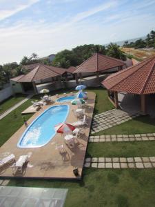 普拉杜Pousada Tropical的享有带椅子和遮阳伞的游泳池的上方景色