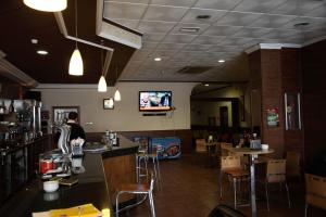 波索阿尔孔波索阿尔孔城市酒店的一间带酒吧的餐厅以及墙上的电视